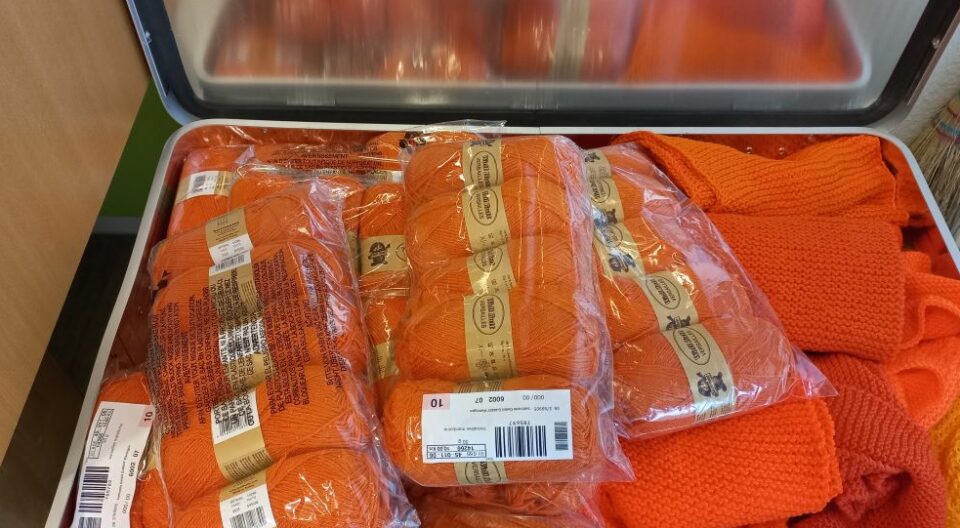 Aluminiumkiste mit orangefarbener Wolle und orangefarbenen Schals